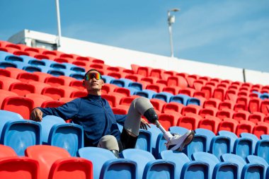 Stadyumdaki koşu pistinde protez bıçaklı Asyalı atletler. Futbol stadyumundaki koltuklar