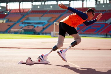 Stadyumdaki koşu pistinde protez bıçaklı Asyalı sporcular.