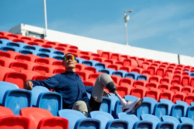 Stadyumdaki koşu pistinde protez bıçaklı Asyalı atletler. Futbol stadyumundaki koltuklar