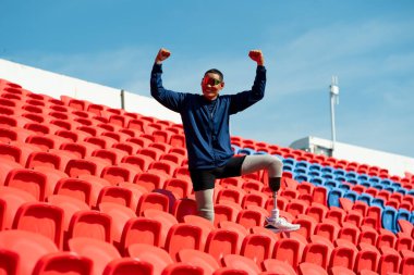 Stadyumdaki koşu pistinde protez bıçaklı Asyalı atletler. Futbol stadyumundaki koltuklar