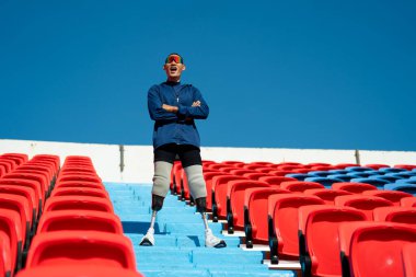 Stadyumdaki koşu pistinde protez bıçaklı Asyalı atletler. Futbol stadyumundaki koltuklar