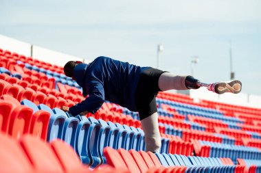 Stadyumdaki koşu pistinde protez bıçaklı Asyalı atletler. Futbol stadyumundaki koltuklar
