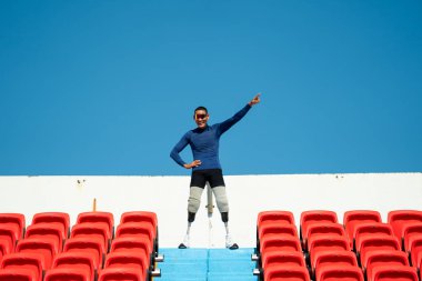 Stadyumdaki koşu pistinde protez bıçaklı Asyalı atletler. Futbol stadyumundaki koltuklar