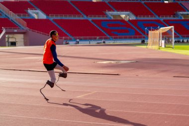 Stadyumdaki koşu pistinde protez bıçaklı Asyalı sporcular.