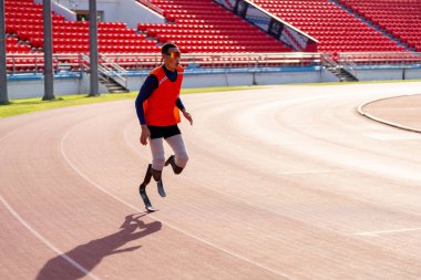 Stadyumdaki koşu pistinde protez bıçaklı Asyalı sporcular.