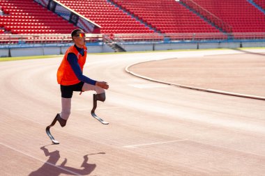 Stadyumdaki koşu pistinde protez bıçaklı Asyalı sporcular.