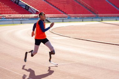 Stadyumdaki koşu pistinde protez bıçaklı Asyalı sporcular.