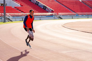 Stadyumdaki koşu pistinde protez bıçaklı Asyalı sporcular.
