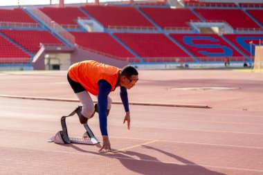 Stadyumdaki koşu pistinde protez bıçaklı Asyalı sporcular.