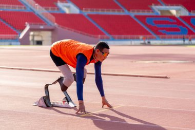 Stadyumdaki koşu pistinde protez bıçaklı Asyalı sporcular.
