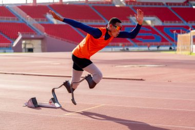 Stadyumdaki koşu pistinde protez bıçaklı Asyalı sporcular.