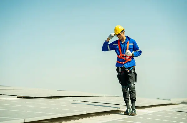 Professional engineer checking solar roof panel on the factory rooftop under sunlight. Engineer having service job of electrical renewable eco energy