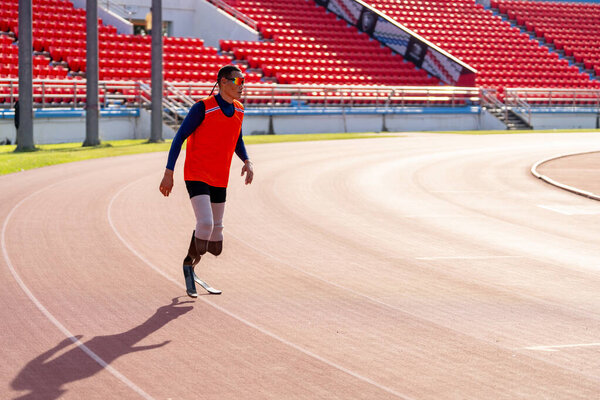Азиатские параатлеты с протезными лезвиями бегают на беговой дорожке на стадионе.