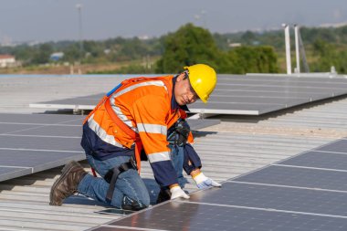 Uzman teknisyen profesyonel mühendis güneş ışığı altında fabrikanın çatısına güneş paneli kurarken üst görüntüyü kontrol ediyor. Elektrik yenilenebilir eko enerji hizmeti veren mühendisler
