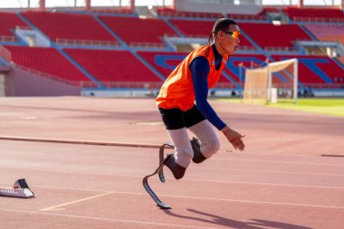 Stadyumdaki koşu pistinde protez bıçaklı Asyalı sporcular.