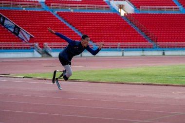 Stadyumdaki koşu pistinde protez bıçaklı Asyalı sporcular.