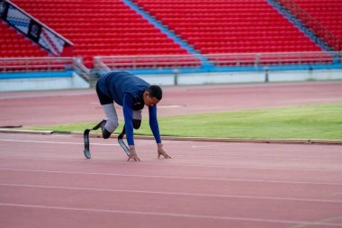 Stadyumdaki koşu pistinde protez bıçaklı Asyalı sporcular.