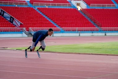 Stadyumdaki koşu pistinde protez bıçaklı Asyalı sporcular.
