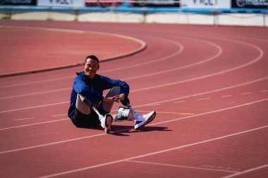 Stadyumdaki koşu pistinde protez bıçaklı Asyalı sporcular.