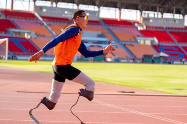 Stadyumdaki koşu pistinde protez bıçaklı Asyalı sporcular.