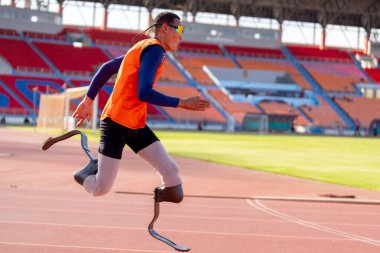 Stadyumdaki koşu pistinde protez bıçaklı Asyalı sporcular.