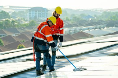 Uzman teknisyen profesyonel mühendis güneş ışığı altında fabrikanın çatısına güneş paneli kurarken üst görüntüyü kontrol ediyor. Elektrik yenilenebilir eko enerji hizmeti veren mühendisler