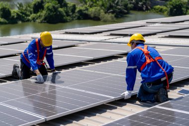 Profesyonel mühendisler güneş ışığı altında güneş çatılarını kontrol ediyorlar. Elektrik yenilenebilir enerji hizmeti veren mühendisler