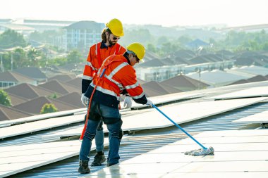 Uzman teknisyen profesyonel mühendis güneş ışığı altında fabrikanın çatısına güneş paneli kurarken üst görüntüyü kontrol ediyor. Elektrik yenilenebilir eko enerji hizmeti veren mühendisler