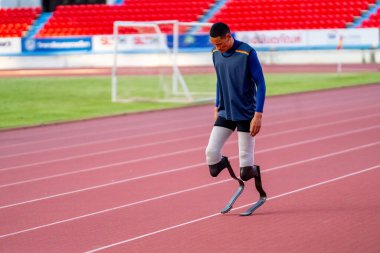 Stadyumdaki koşu pistinde protez bıçaklı Asyalı sporcular.