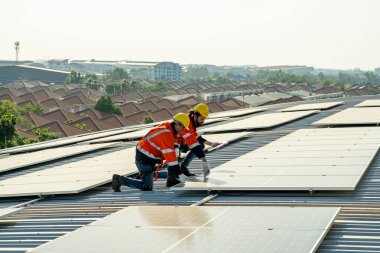 Uzman teknisyen profesyonel mühendis güneş ışığı altında fabrikanın çatısına güneş paneli kurarken üst görüntüyü kontrol ediyor. Elektrik yenilenebilir eko enerji hizmeti veren mühendisler