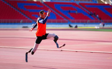 Stadyumdaki koşu pistinde protez bıçaklı Asyalı sporcular.