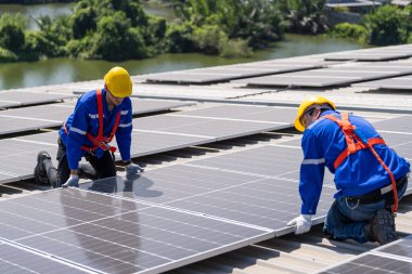 Uzman teknisyen profesyonel mühendis güneş ışığı altında fabrikanın çatısına güneş paneli kurarken üst görüntüyü kontrol ediyor. Elektrik yenilenebilir eko enerji hizmeti veren mühendisler