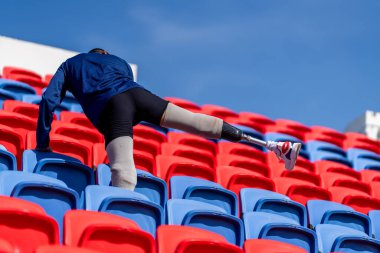 Stadyumdaki koşu pistinde protez bıçaklı Asyalı atletler. Futbol stadyumundaki koltuklar