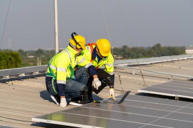 Profesyonel mühendisler güneş ışığı altında güneş çatılarını kontrol ediyorlar. Elektrik yenilenebilir enerji hizmeti veren mühendisler