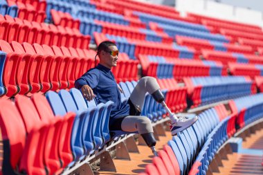 Stadyumdaki koşu pistinde protez bıçaklı Asyalı atletler. Futbol stadyumundaki koltuklar