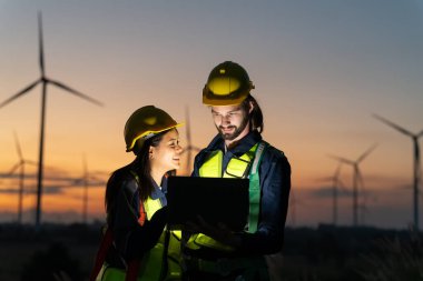 Rüzgar türbinlerini inceleyen iki çok ırklı sanayi işçisi. Üretim ekosistemi temiz yeşil enerjili kırsal alan