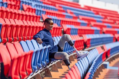 Stadyumdaki koşu pistinde protez bıçaklı Asyalı atletler. Futbol stadyumundaki koltuklar