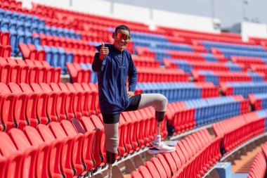 Stadyumdaki koşu pistinde protez bıçaklı Asyalı atletler. Futbol stadyumundaki koltuklar