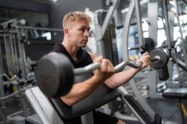 Spor salonundaki yakışıklı, formda adam halter kaldırıyor.