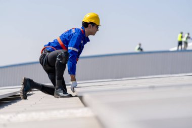 Profesyonel mühendis güneş ışığı altında fabrikanın çatısındaki güneş panelini kontrol ediyor. Elektrik yenilenebilir eko enerji hizmeti veren bir mühendis.