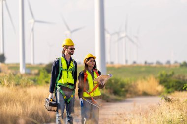 Rüzgar türbinlerini inceleyen iki çok ırklı sanayi işçisi. Üretim ekosistemi temiz yeşil enerjili kırsal alan