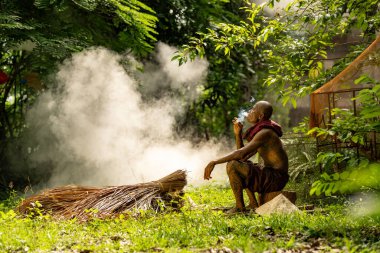 Beyaz elbiseli bir adam bahçede oturuyor.