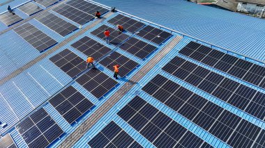 Hava manzarası, güneş panelleri büyük bir binanın çatısına kurulmuş. Güneş pili çiftliği enerji santrali eko teknolojisi. Bir fotovoltaik enerji santralindeki güneş pili panellerinin peyzajı