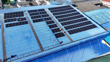 Hava manzarası, güneş panelleri büyük bir binanın çatısına kurulmuş. Güneş pili çiftliği enerji santrali eko teknolojisi. Bir fotovoltaik enerji santralindeki güneş pili panellerinin peyzajı