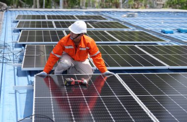 Teknoloji güneş pili, mühendislik hizmeti kurulum güneş pili fabrika endüstrisinin çatısında. Fabrikanın çatısındaki güneş pilini inceleyen teknisyen. 