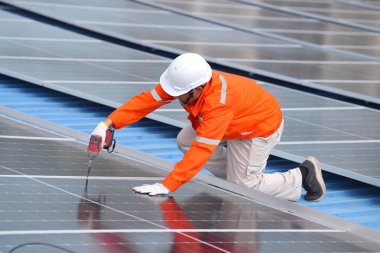 Teknoloji güneş pili, mühendislik hizmeti kurulum güneş pili fabrika endüstrisinin çatısında. Fabrikanın çatısındaki güneş pilini inceleyen teknisyen. 