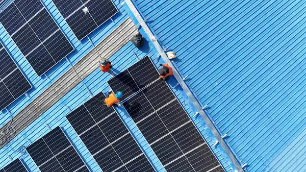 Hava manzarası, güneş panelleri büyük bir binanın çatısına kurulmuş. Güneş pili çiftliği enerji santrali eko teknolojisi. Bir fotovoltaik enerji santralindeki güneş pili panellerinin peyzajı