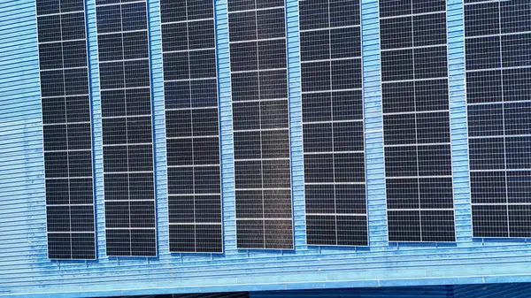 Hava manzarası, güneş panelleri büyük bir binanın çatısına kurulmuş. Güneş pili çiftliği enerji santrali eko teknolojisi. Bir fotovoltaik enerji santralindeki güneş pili panellerinin peyzajı