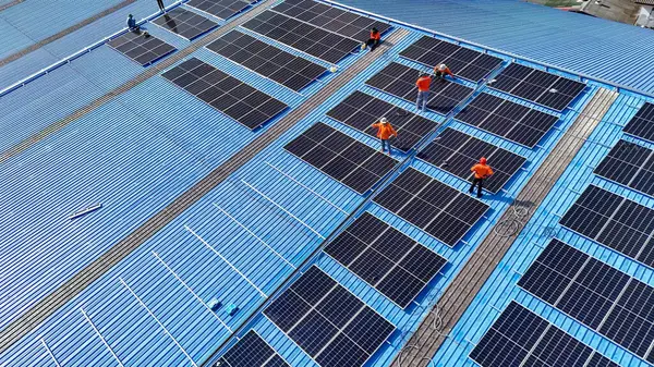 Hava manzarası, güneş panelleri büyük bir binanın çatısına kurulmuş. Güneş pili çiftliği enerji santrali eko teknolojisi. Bir fotovoltaik enerji santralindeki güneş pili panellerinin peyzajı