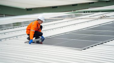 Evin çatısına fotovoltaik güneş modülleri monte eden bir inşaatçı. Güneş paneli sistemi kuran miğferdeki insan mühendisin arka görüntüsü. Alternatif ve yenilenebilir enerji kavramı.